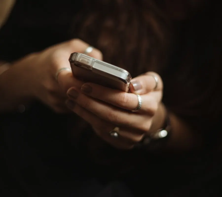 Manos sosteniendo un teléfono en una oficina con luz tenue