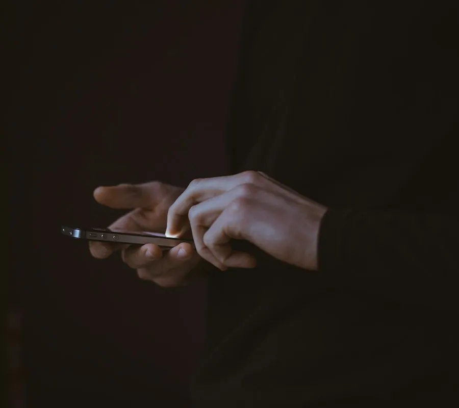 Persona escribiendo en su celular en un espacio oscuro